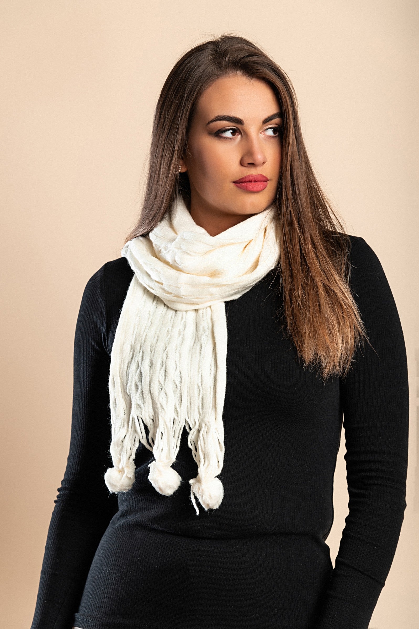 A cozy white knitted scarf with playful pompoms, perfect for winter fashion.