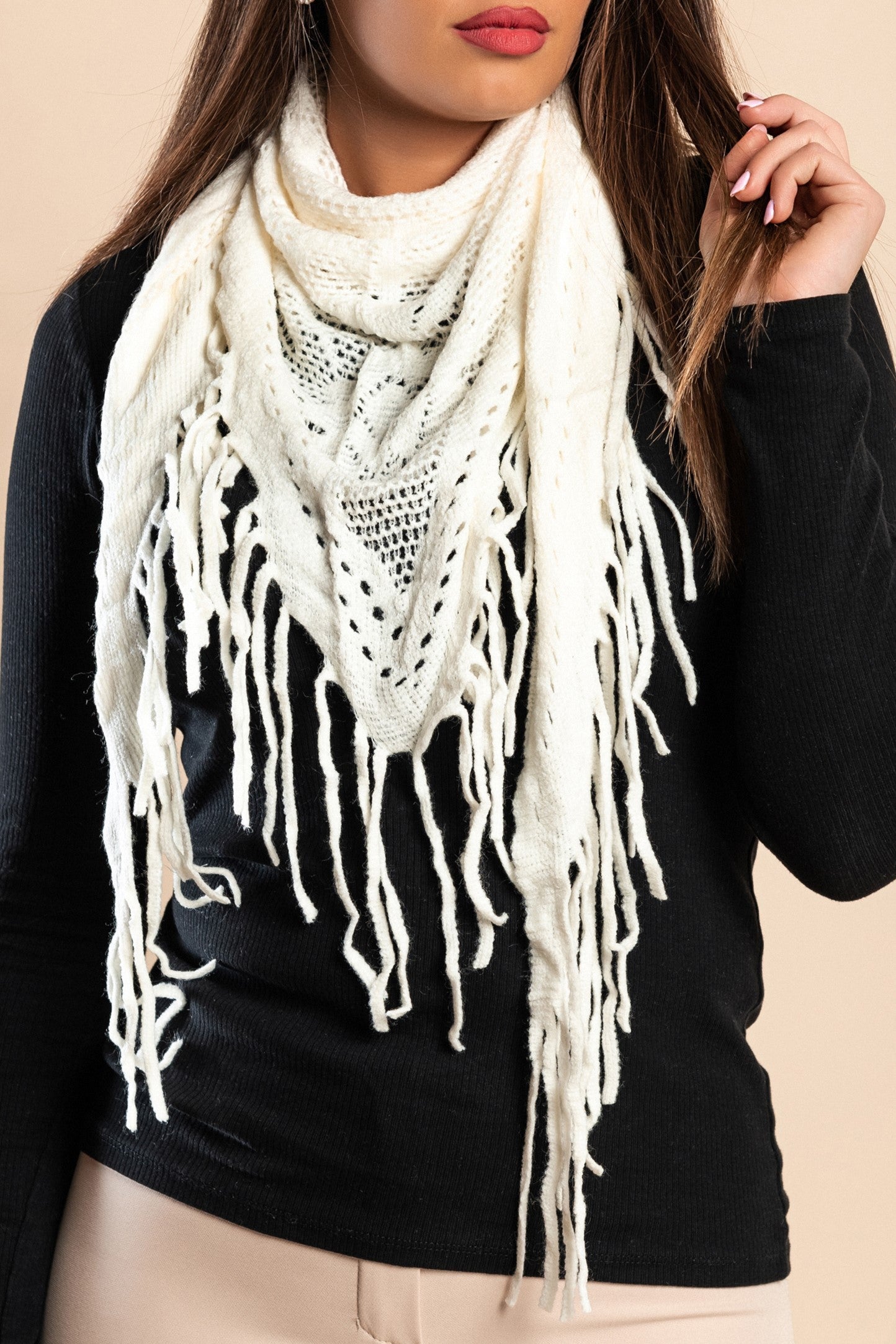 A stylish white knitted triangular scarf with fringes, showcasing its soft texture and elegant design.