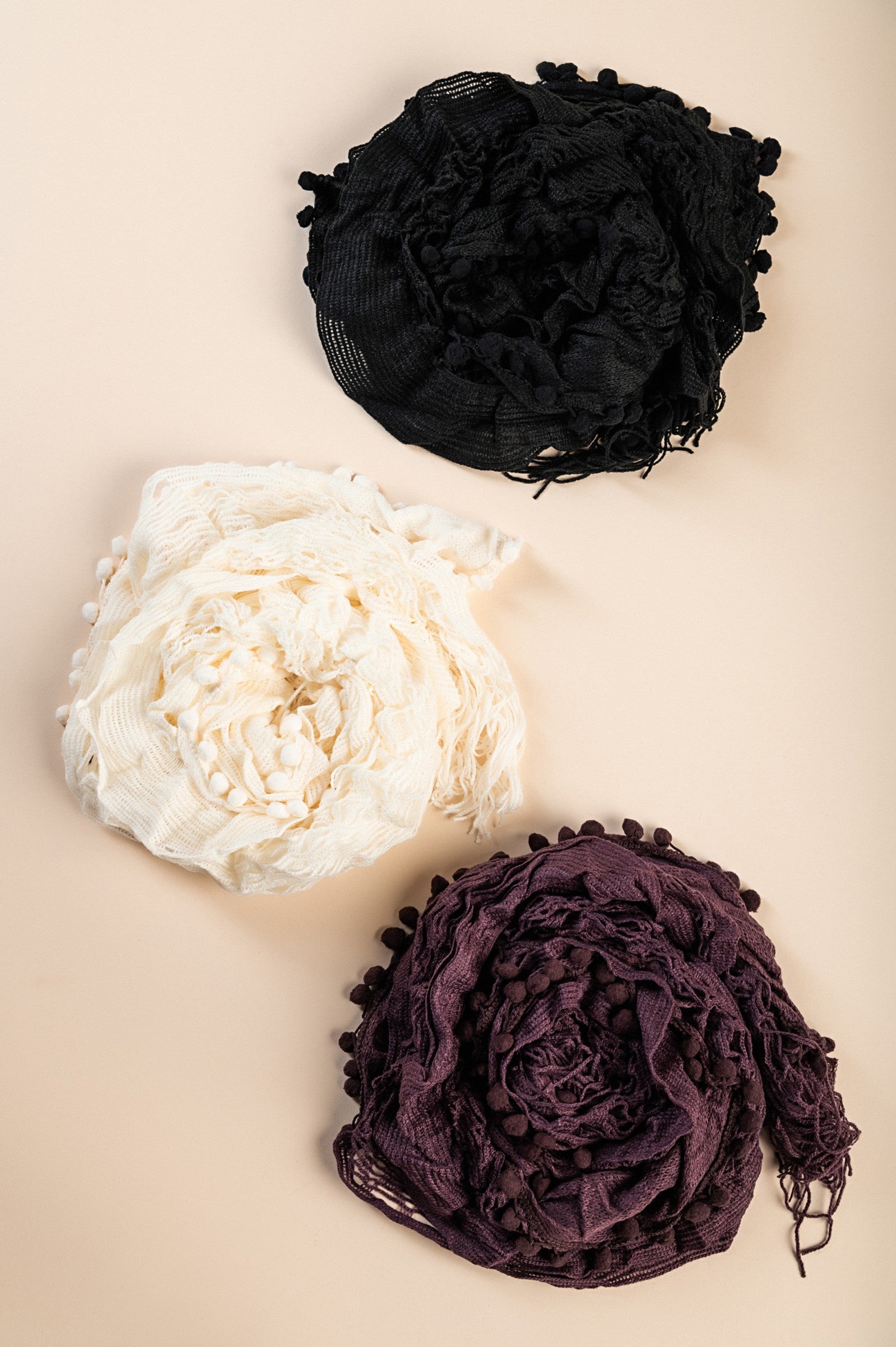 A vibrant set of three knitted scarves in black, white, and purple, showcasing their soft texture and stylish design.