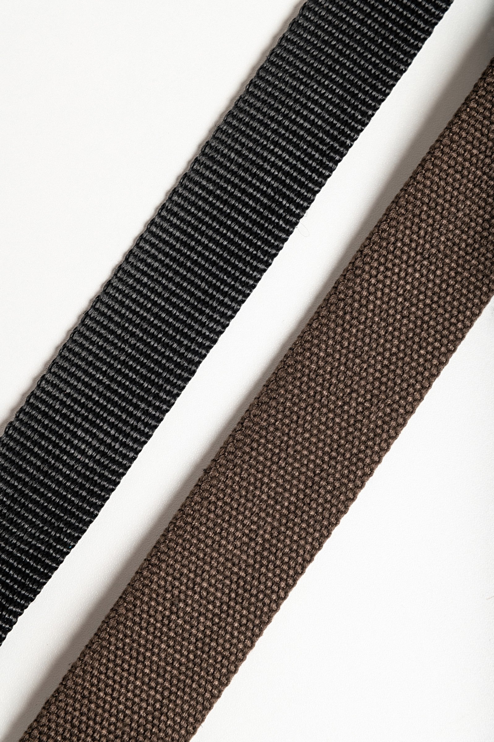 Set of two adjustable belts in brown and black with metal buckles, showcasing durability and style.