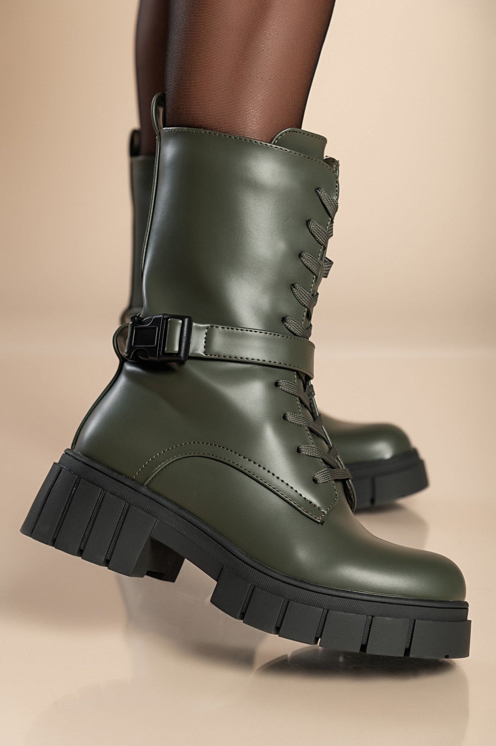 Stylish green lace-up ankle boots with round toe and decorative strap, featuring a zipper closure on the inside.