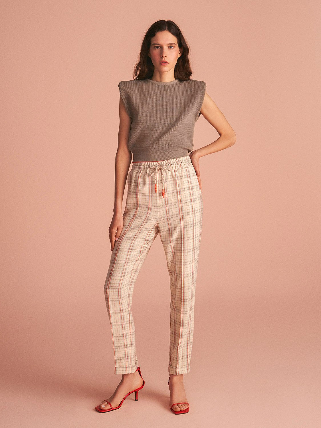 Lace-up plaid pants featuring a high-waisted design, elastic waistband, and cuffed hems, styled on a model.