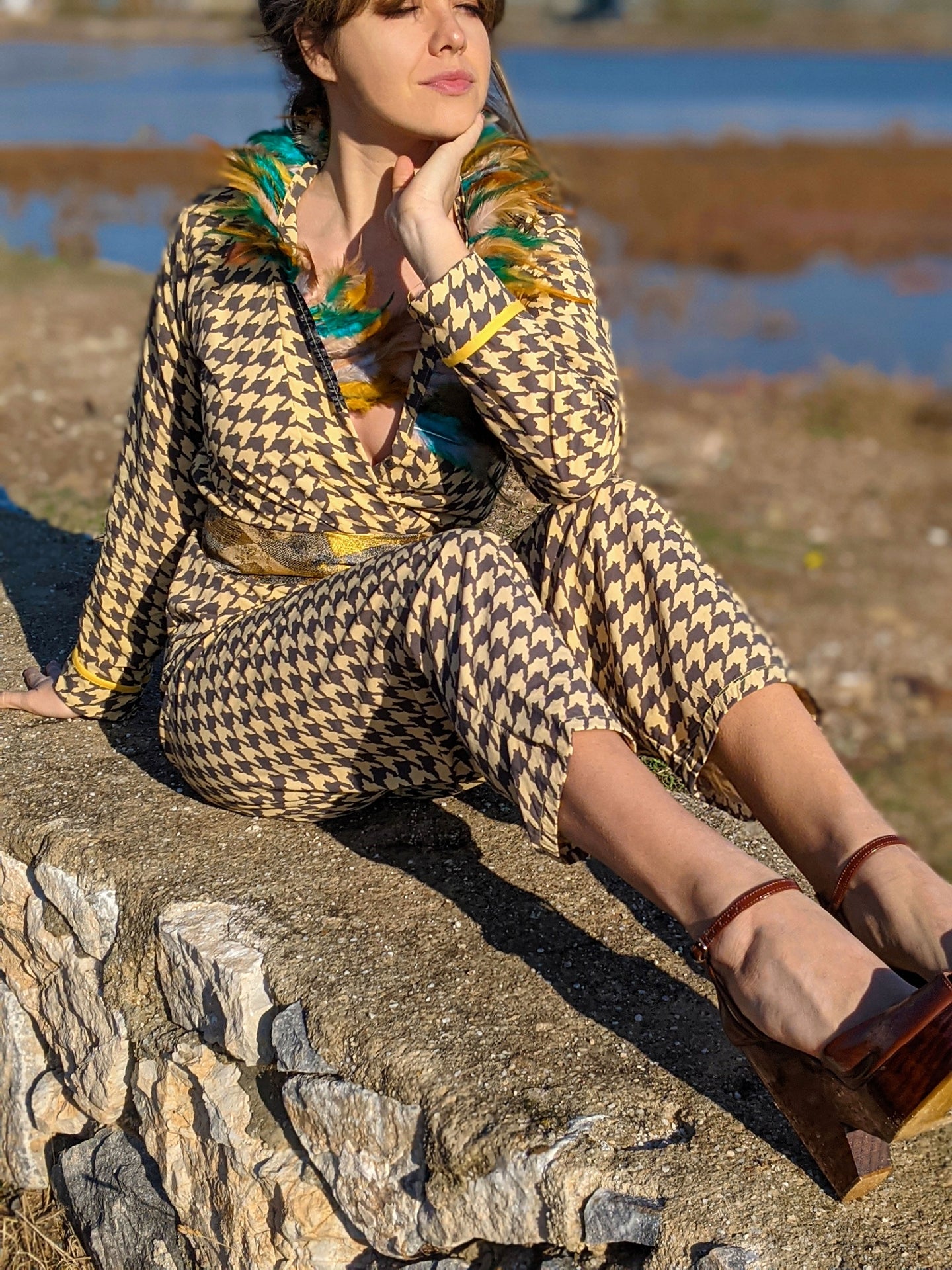 LAGINA jacket and pants suit featuring houndstooth pattern in yellow and tile brown, adorned with colorful feathers and shiny golden waistband.