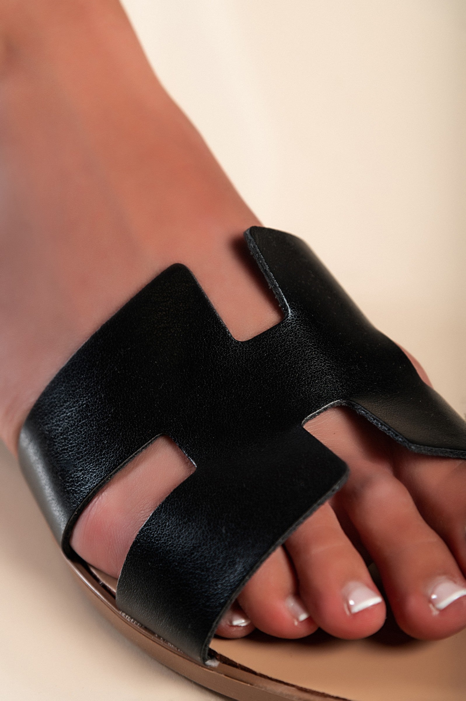 Stylish black leather sandals with a wide strap and square toe, featuring cut-outs for added design.