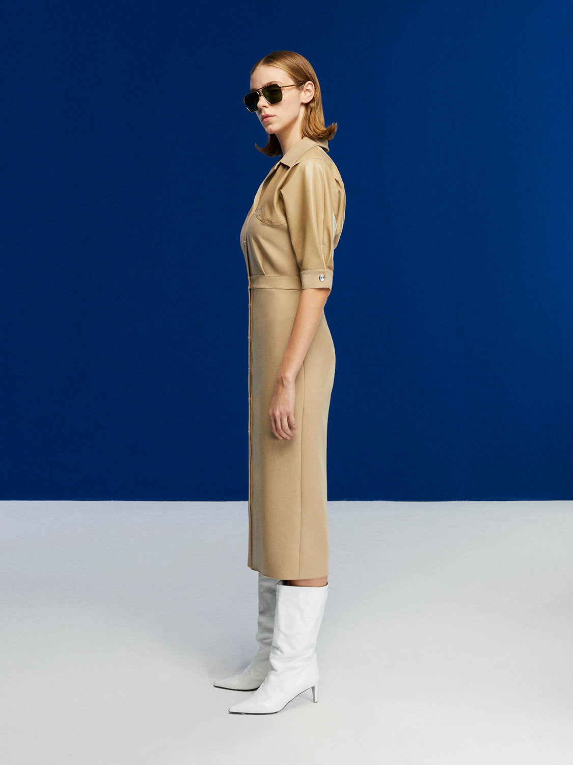 A stylish pleated midi dress featuring faux leather trimming, below-the-elbow sleeves, and a front metal snap button closure.