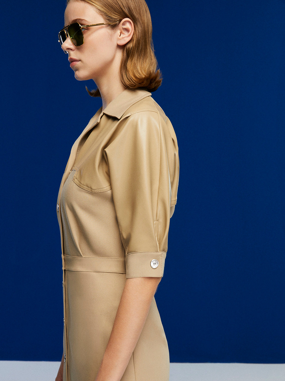 A stylish pleated midi dress featuring faux leather trimming, below-the-elbow sleeves, and a front metal snap button closure.