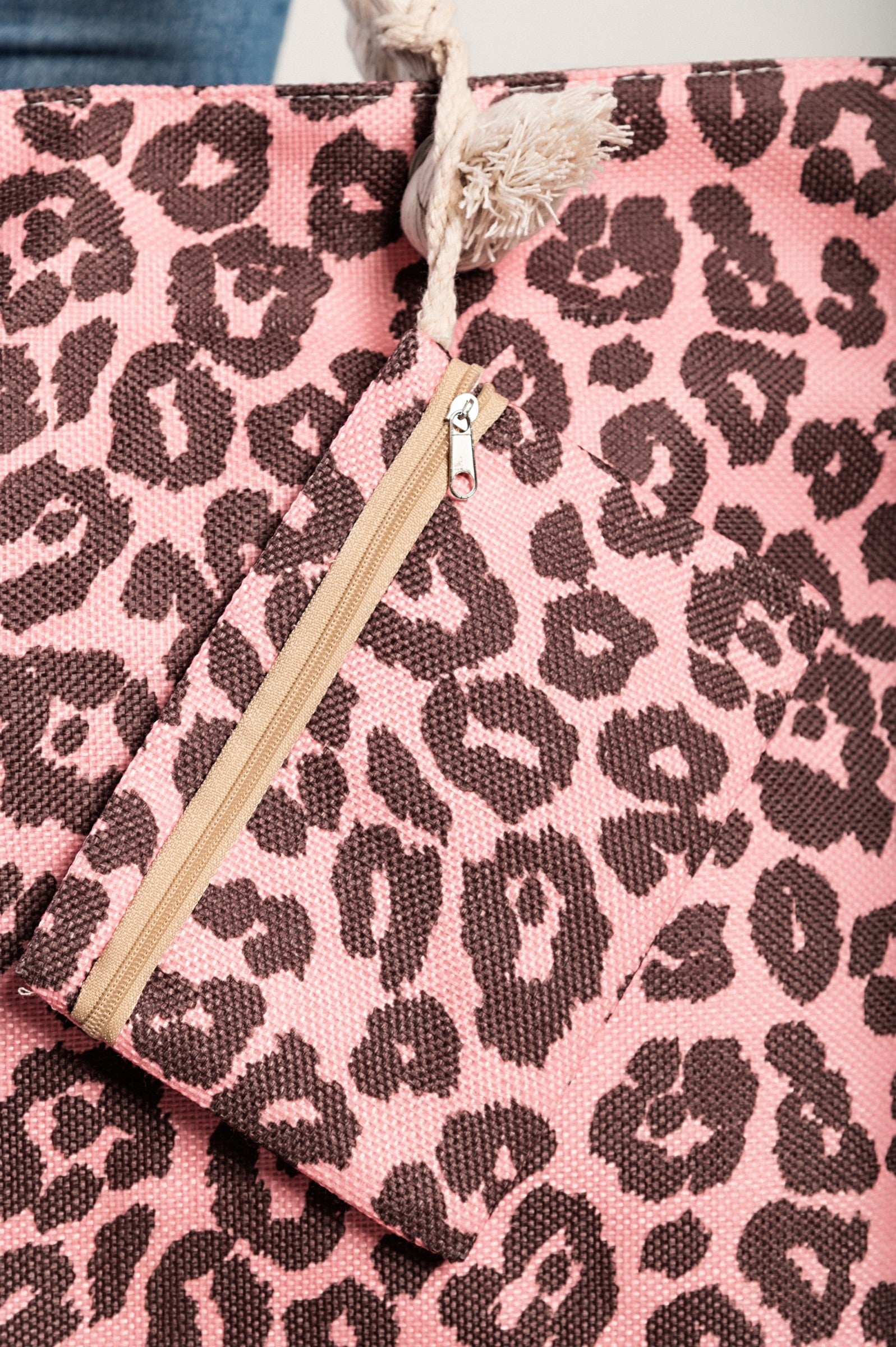 Light pink leopard print beach bag with braided handles and zip closure, featuring an inside pocket and a small matching bag.