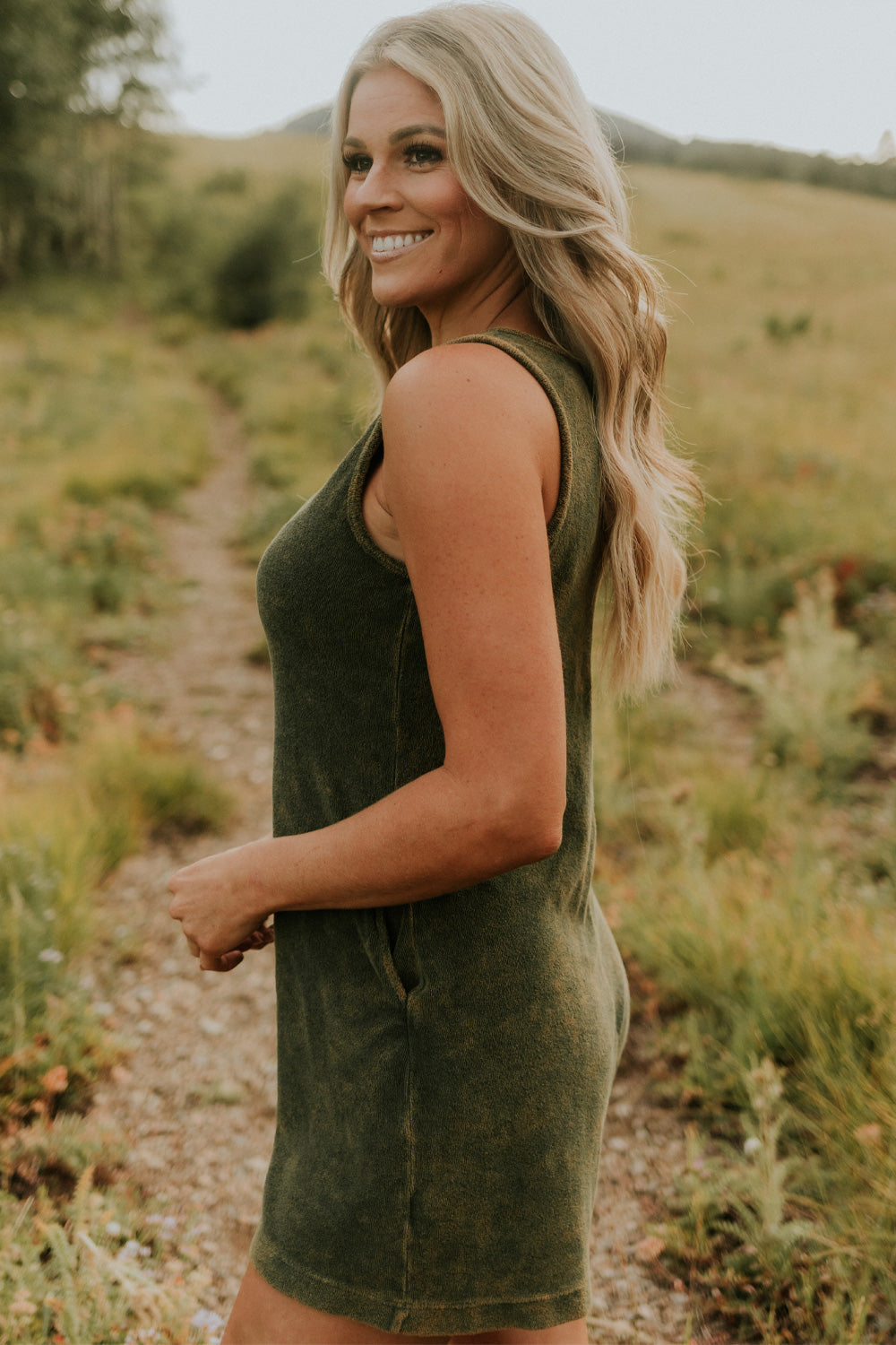 A stylish Let Go Romper made from 100% organic cotton, featuring a unique front seam and button clasp at the back, available in Brown, Olive, and Orange.