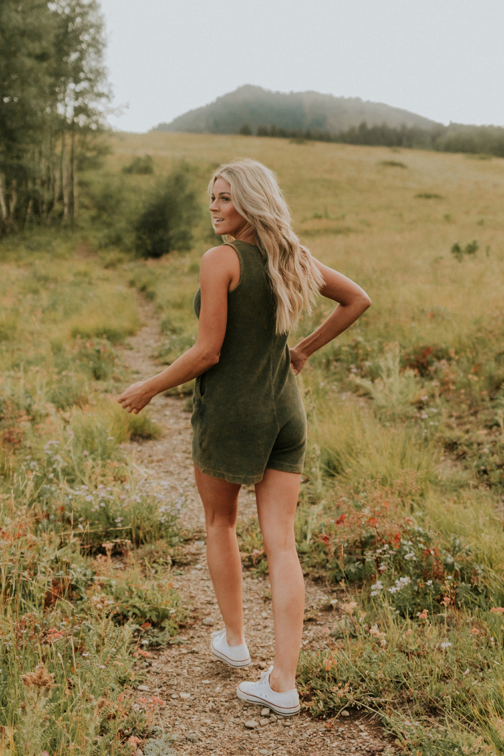 A stylish Let Go Romper made from 100% organic cotton, featuring a unique front seam and button clasp at the back, available in Brown, Olive, and Orange.