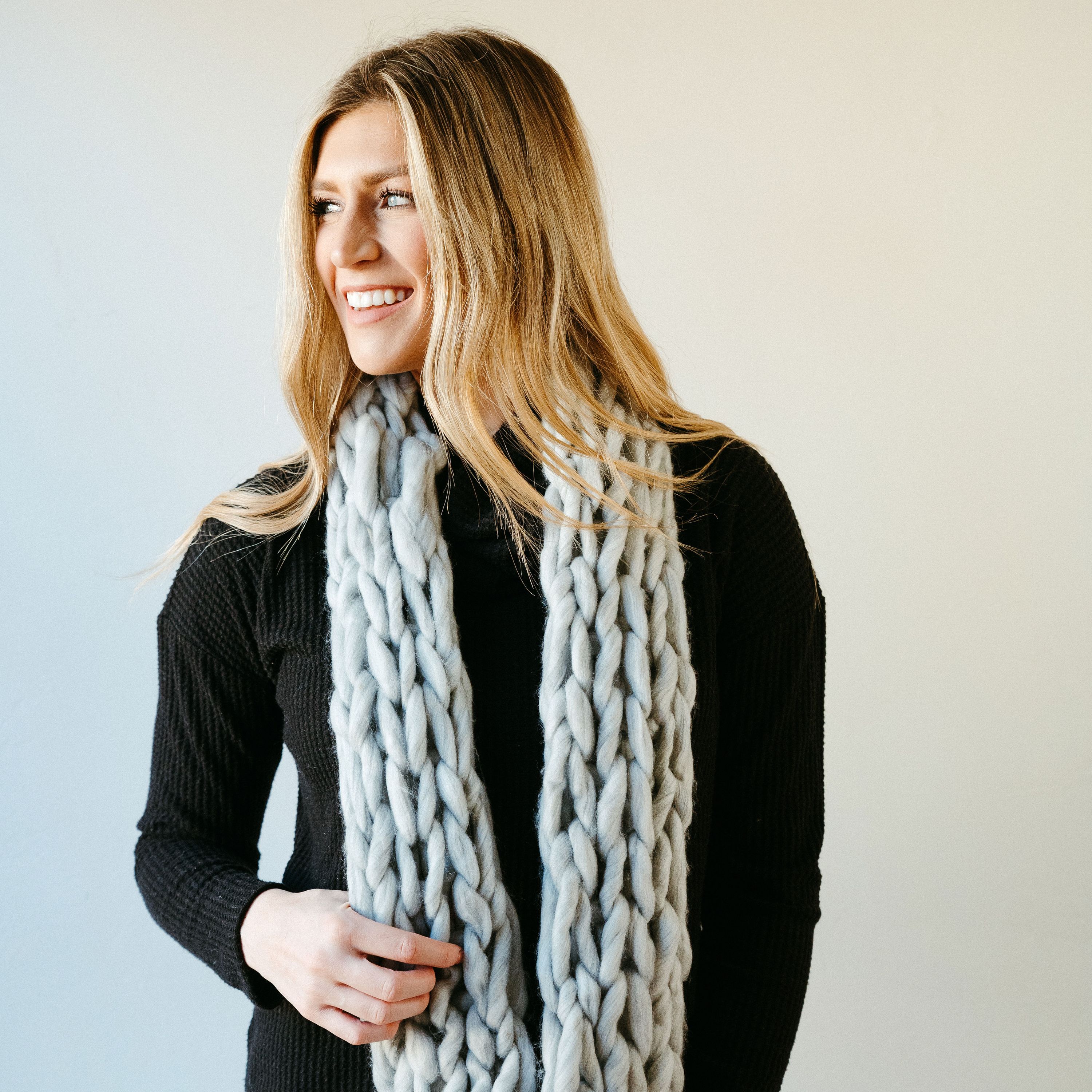 Light gray thick knit infinity scarf draped elegantly, showcasing its soft texture and cozy design, perfect for winter wear.