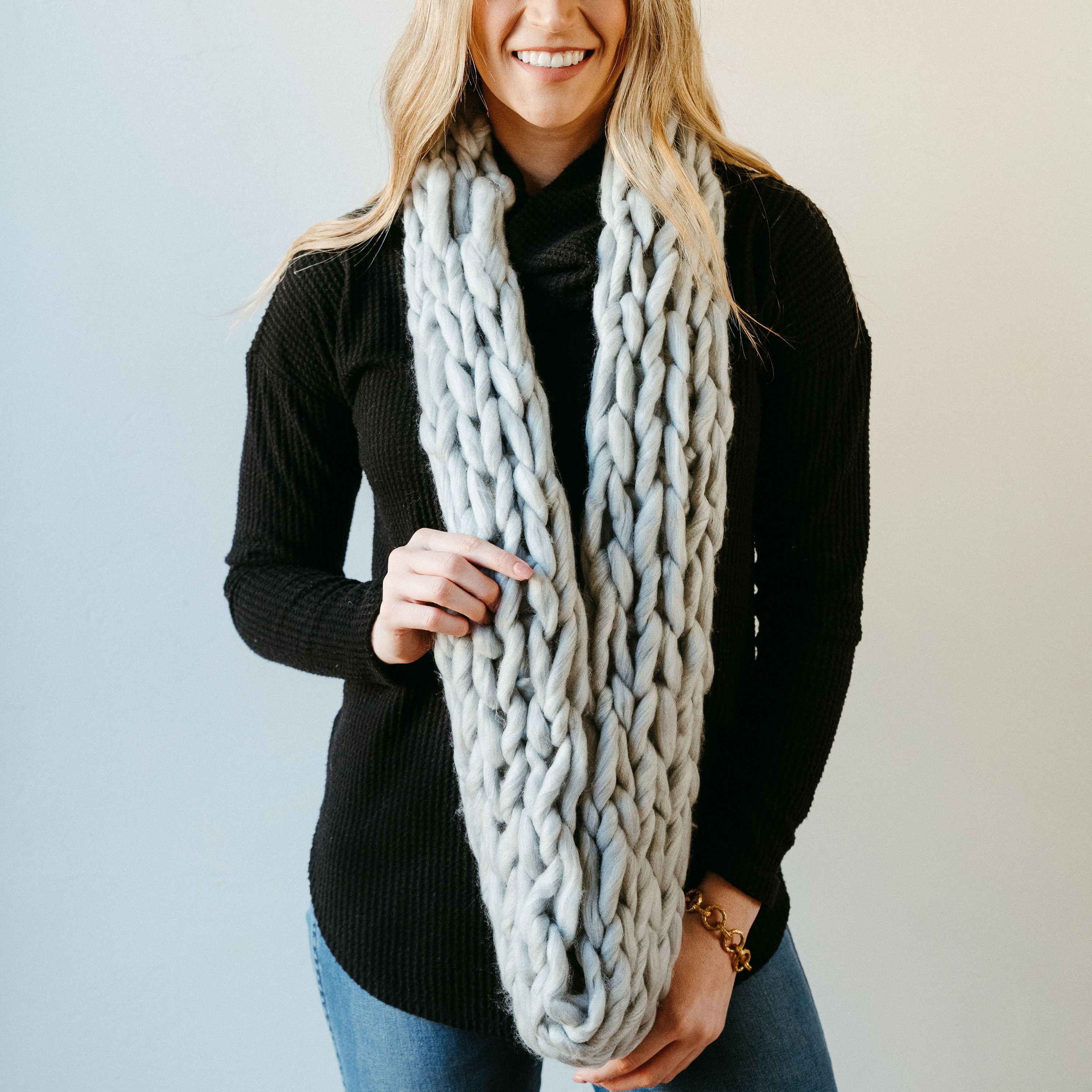 Light gray thick knit infinity scarf draped elegantly, showcasing its soft texture and cozy design, perfect for winter wear.