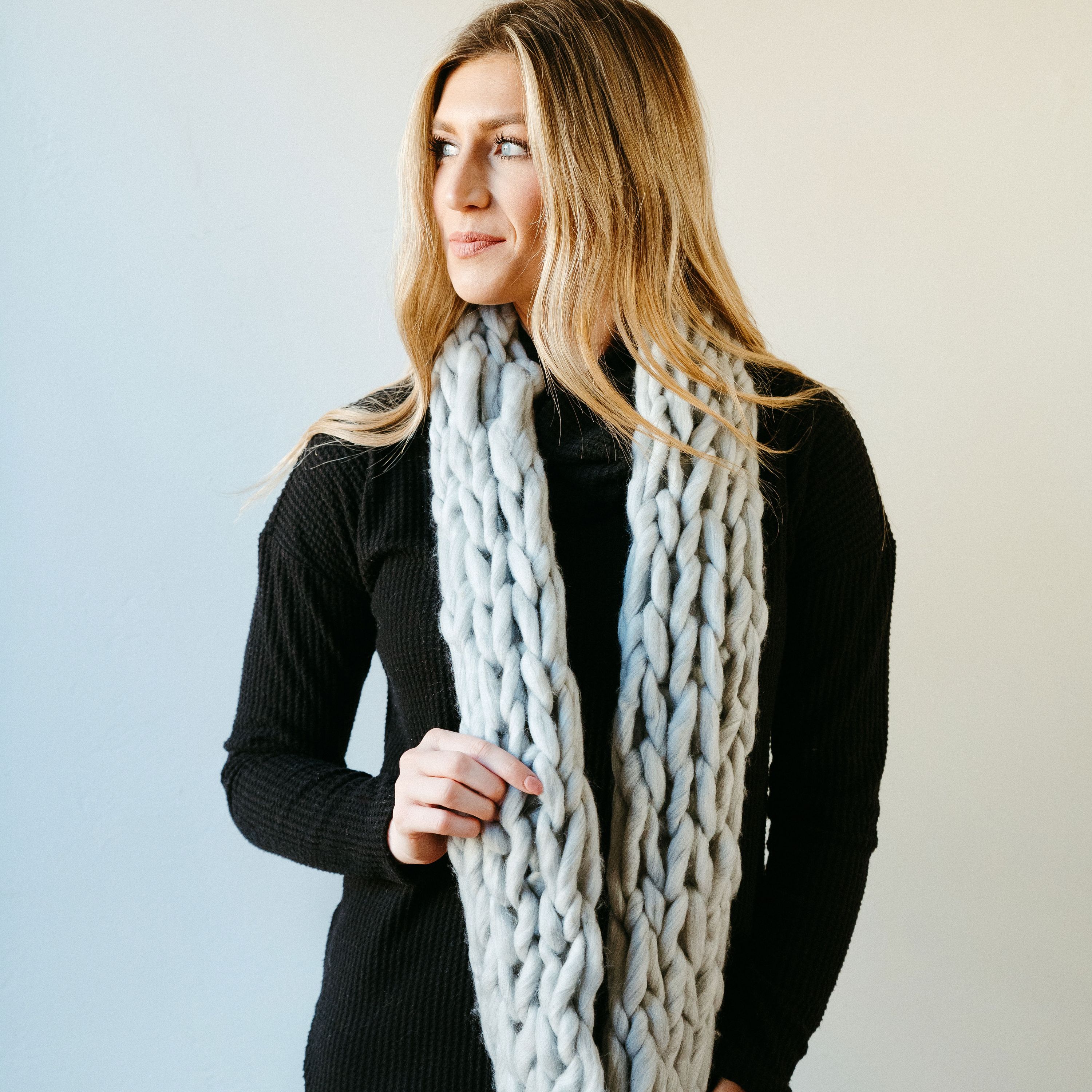 Light gray thick knit infinity scarf draped elegantly, showcasing its soft texture and cozy design, perfect for winter wear.