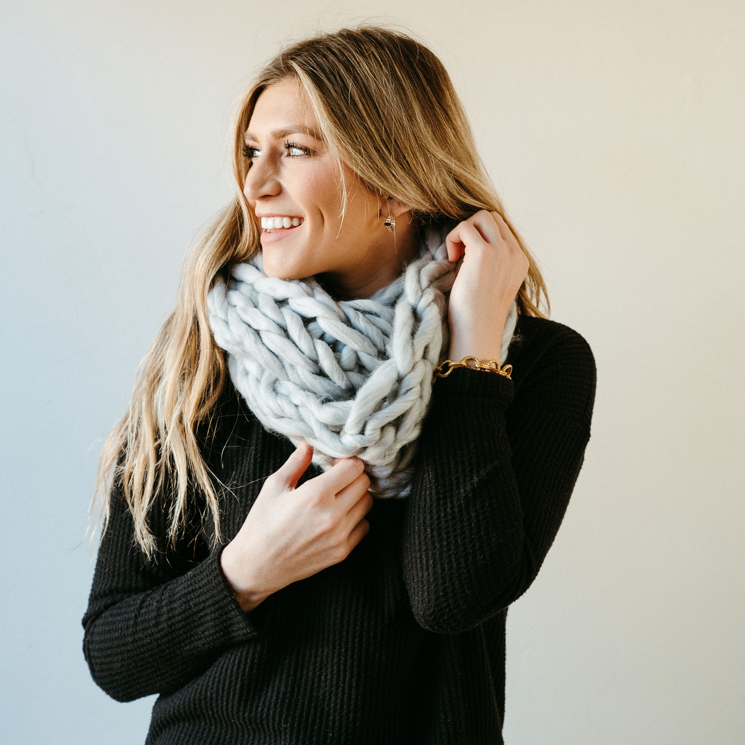 Light gray thick knit infinity scarf draped elegantly, showcasing its soft texture and cozy design, perfect for winter wear.