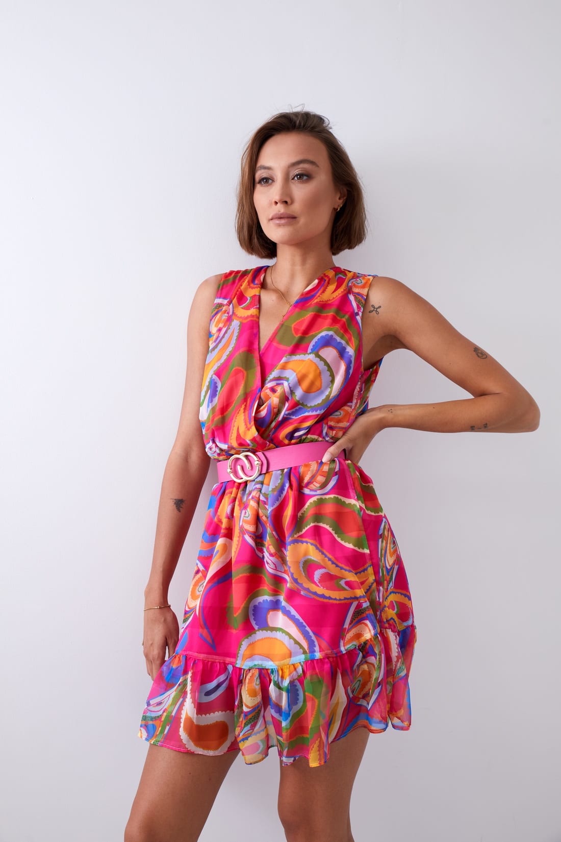 Light patterned dress with a belt in pink and dark blue, featuring a V-envelope neckline and ruffled bottom.