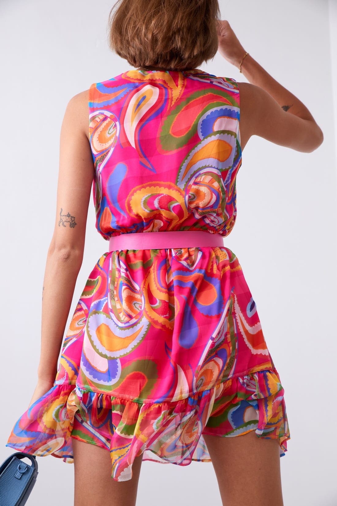 Light patterned dress with a belt in pink and dark blue, featuring a V-envelope neckline and ruffled bottom.