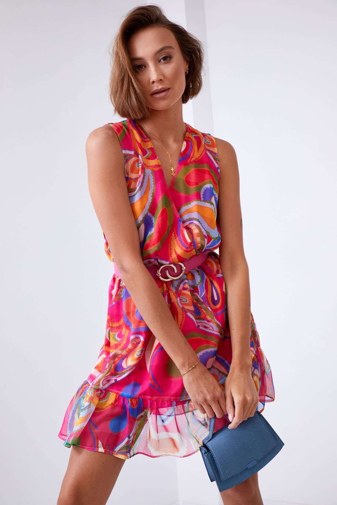 Light patterned dress with a belt in pink and dark blue, featuring a V-envelope neckline and ruffled bottom.