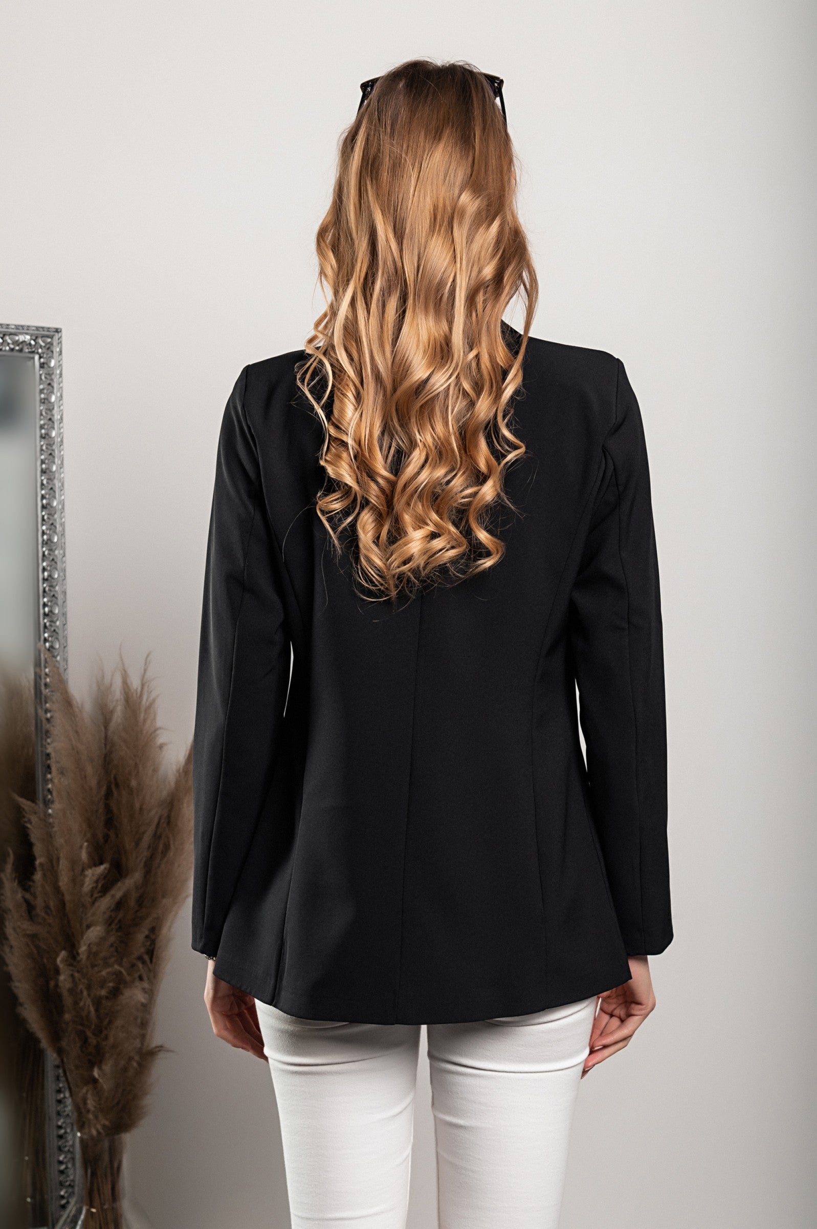 Long black blazer with decorative buttons and classic collar, featuring padded shoulders and fully lined interior.