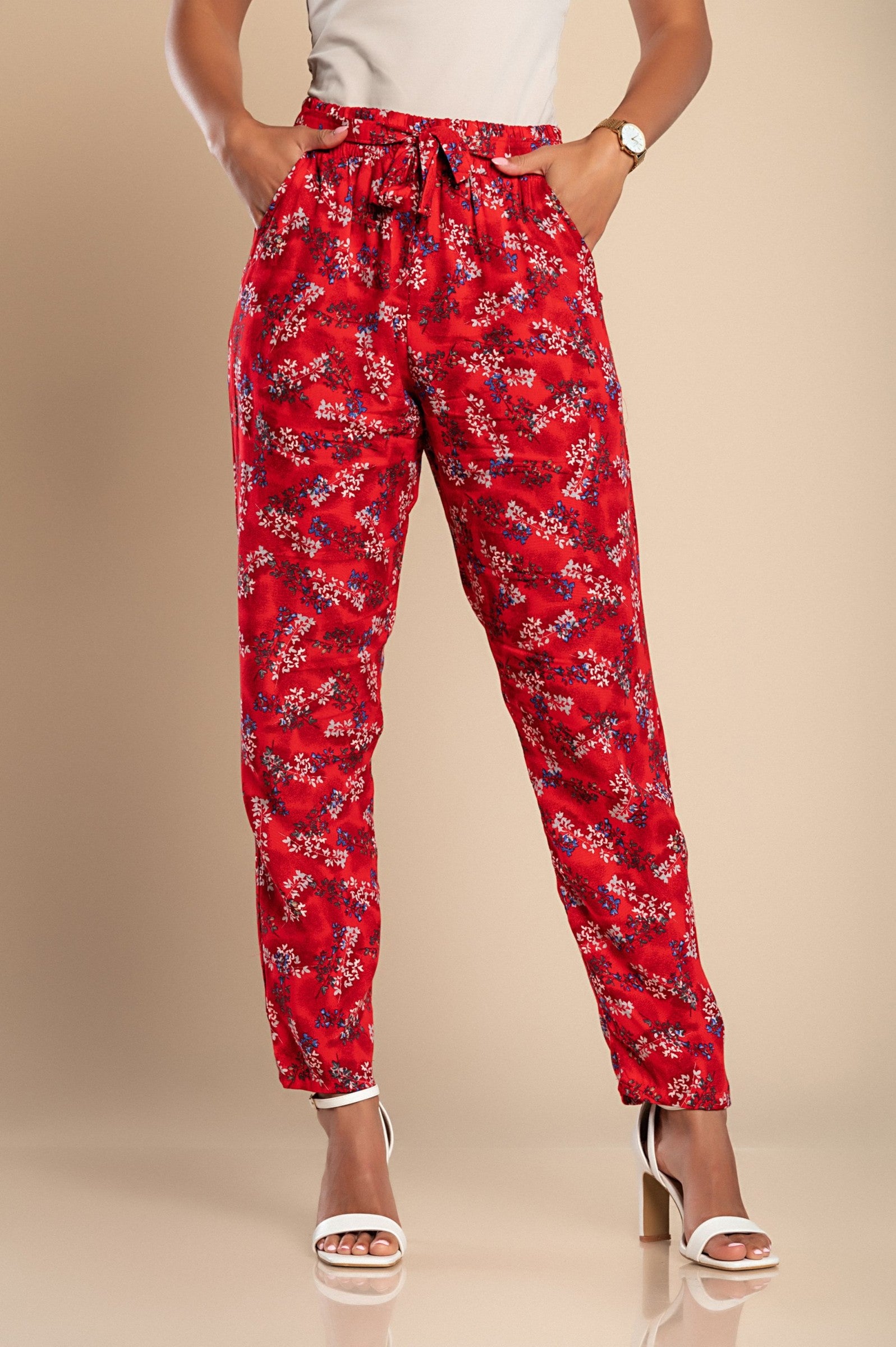 Long red cotton trousers featuring a vibrant floral print, designed for comfort with an elasticated waist and side pockets.