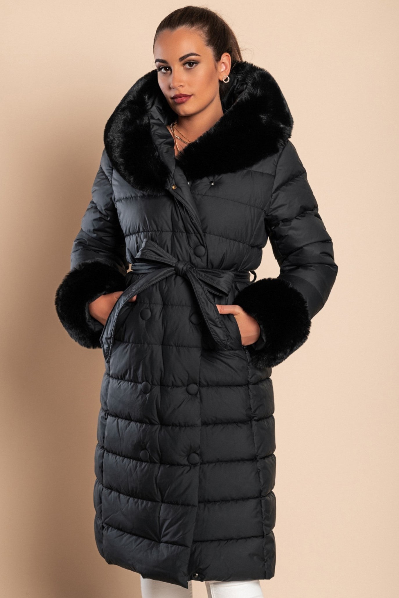 Long padded winter jacket in black with removable faux fur collar, side pockets, and decorative belt, perfect for winter wear.