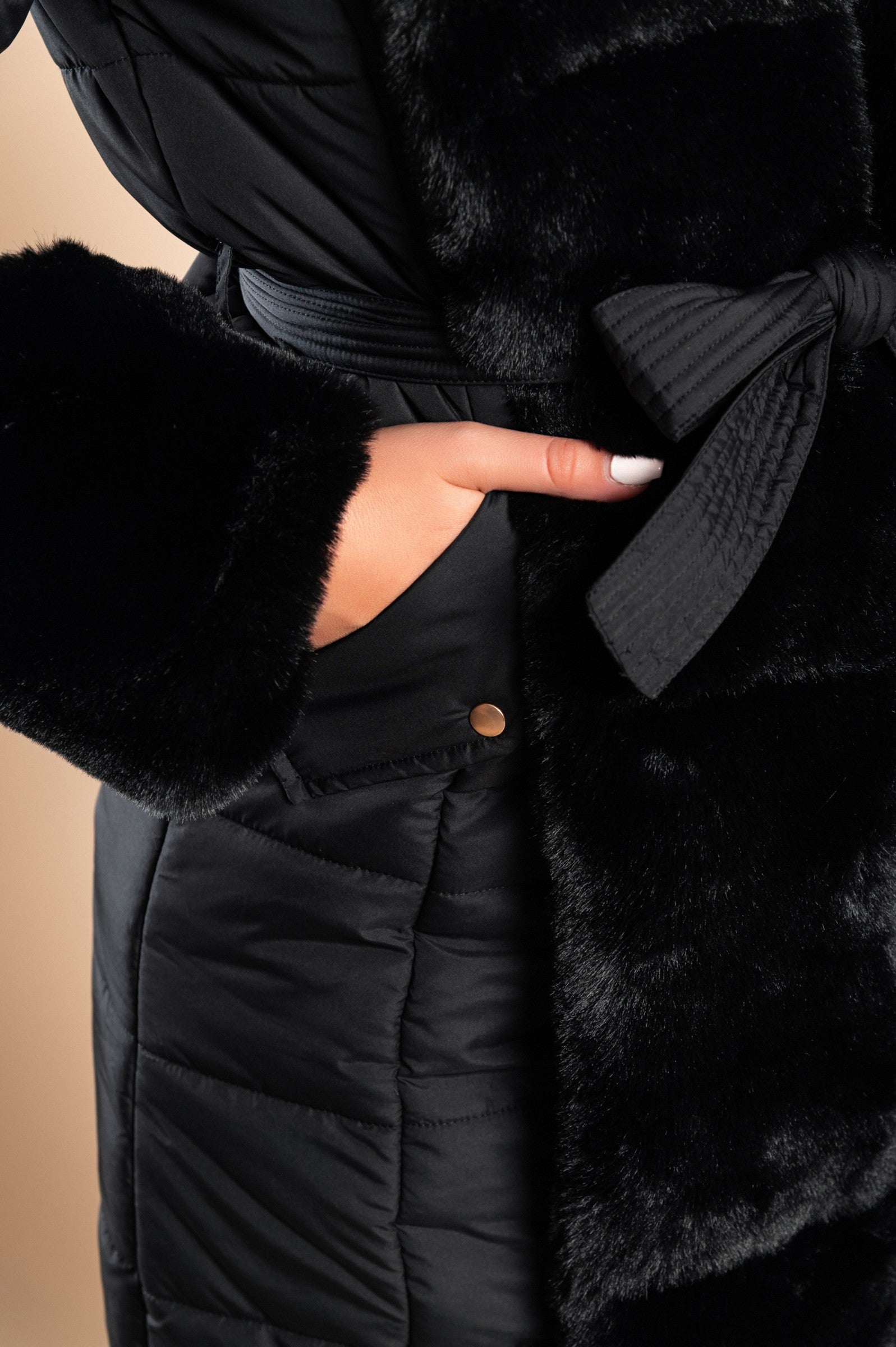 Long padded winter jacket in black with removable faux fur trim, side pockets, and metal zipper closure.