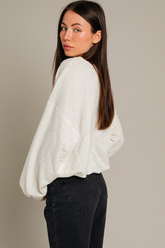 A stylish Long Sleeve Malibu Graphic Pullover displayed on a model, showcasing its trendy design and comfortable fit.