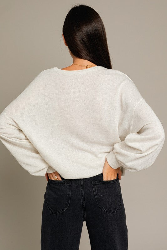 A stylish Long Sleeve Malibu Graphic Pullover displayed on a model, showcasing its trendy design and comfortable fit.