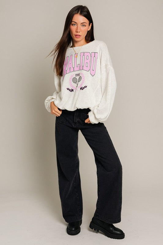 A stylish Long Sleeve Malibu Graphic Pullover displayed on a model, showcasing its trendy design and comfortable fit.