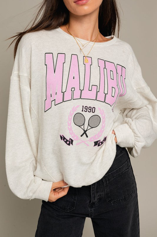 A stylish Long Sleeve Malibu Graphic Pullover displayed on a model, showcasing its trendy design and comfortable fit.