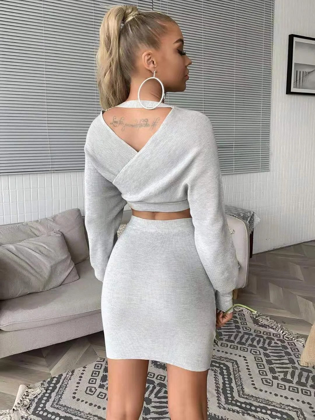 A stylish long sleeve sweater two piece mini skirt set featuring a cropped top with V-neck and a high-rise bodycon mini skirt, perfect for chic outings.