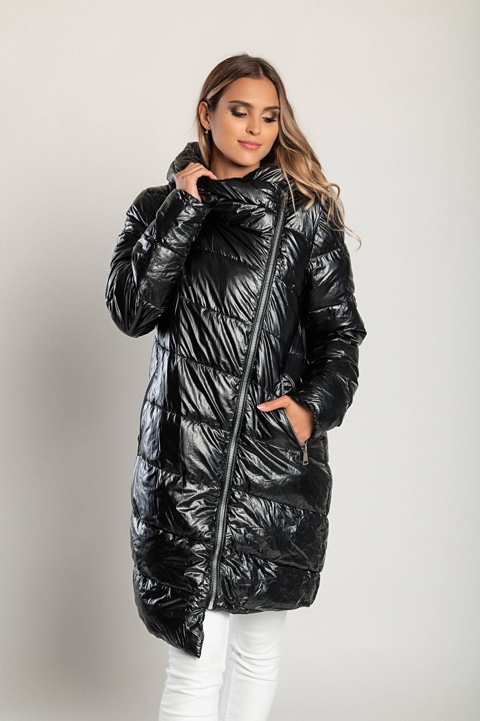 Long black winter jacket with hood and high collar, featuring a quilted design and zip closure.