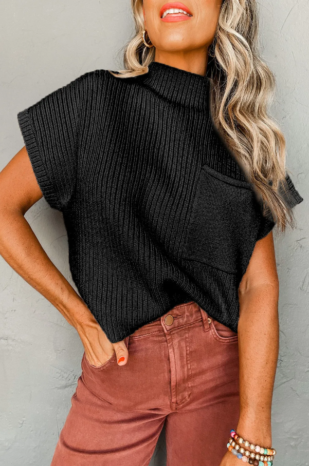 Loose knitted black top with short sleeves and decorative front pocket, showcasing a stylish and comfortable design.