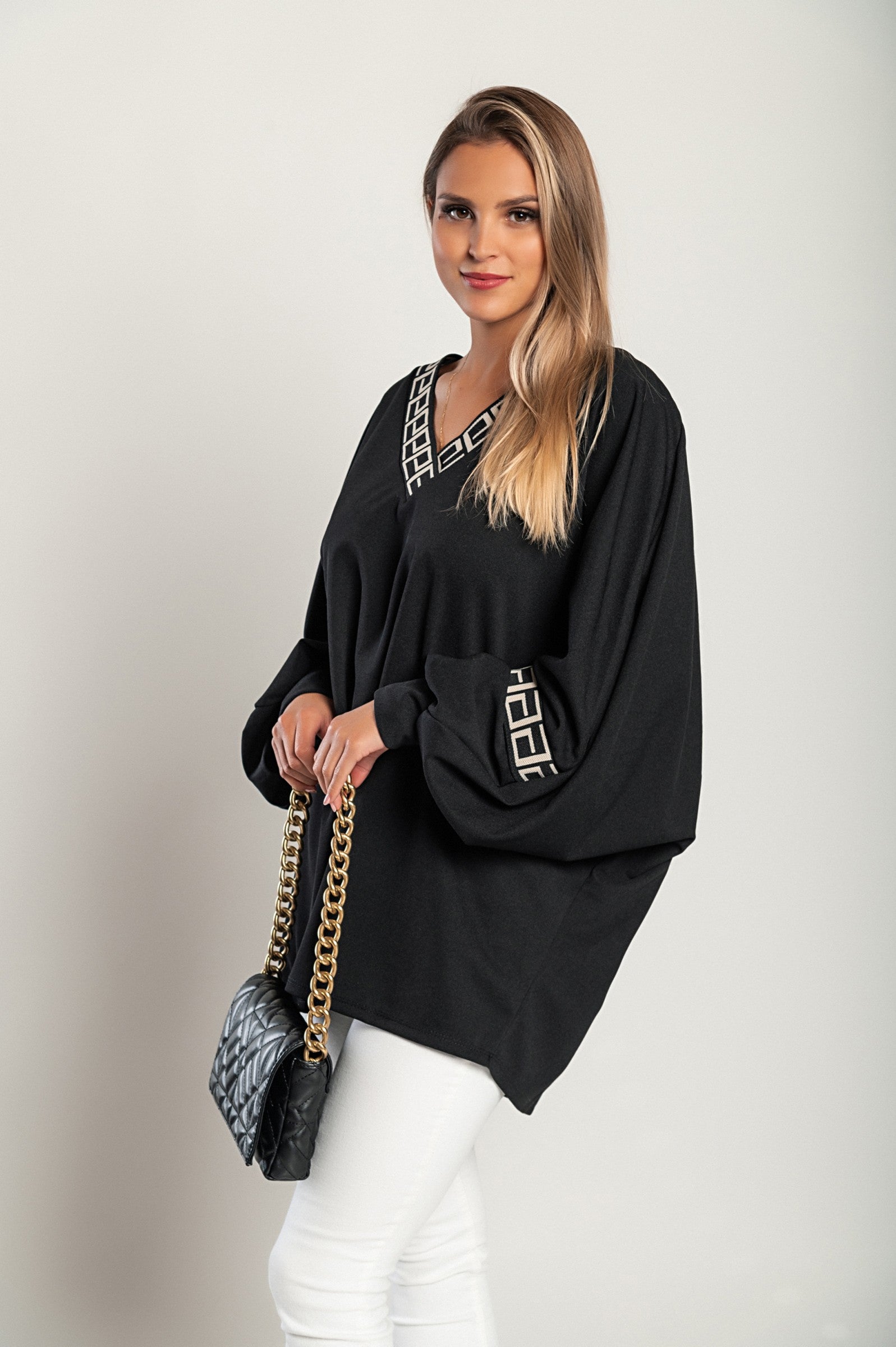 Loose black top featuring a geometric print, deep V-neckline, and long sleeves, designed for comfort and style.