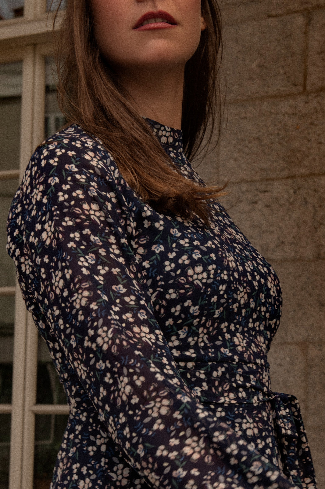 Maelys Dress featuring a short fit and flare design with a navy blue ditsy flower print, mock neck, and semi-sheer long sleeves.