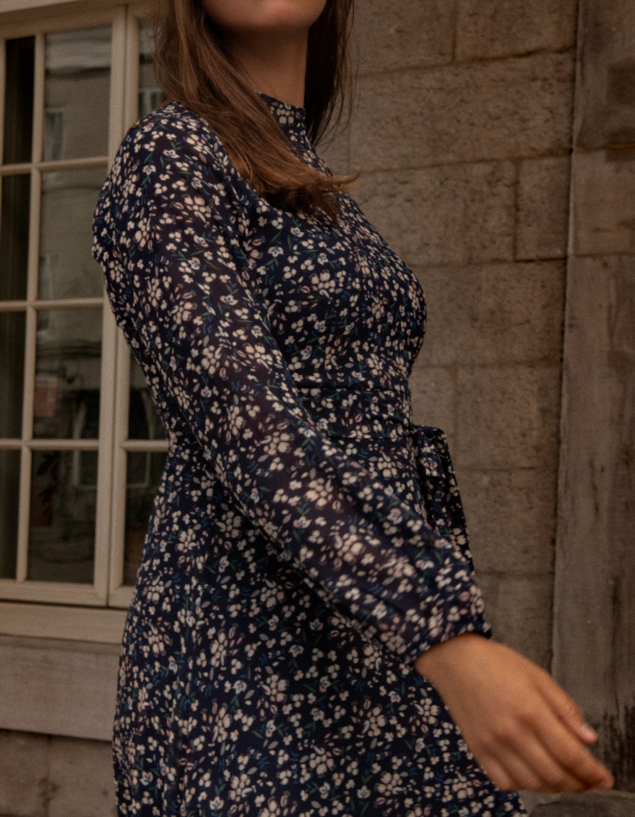 Maelys Dress featuring a short fit and flare design with a navy blue ditsy flower print, mock neck, and semi-sheer long sleeves.