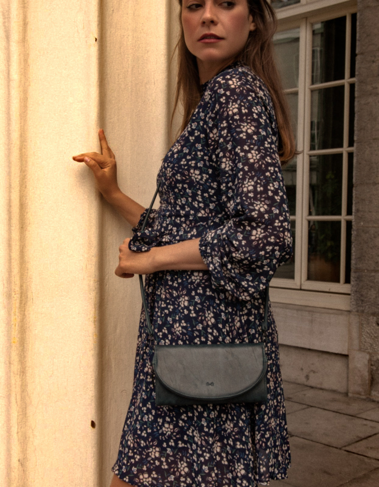 Maelys Dress featuring a short fit and flare design with a navy blue ditsy flower print, mock neck, and semi-sheer long sleeves.