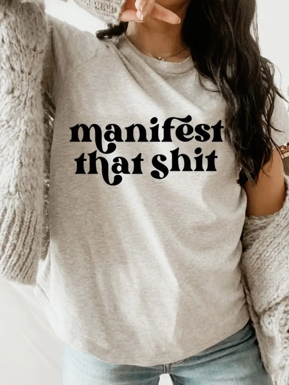 A stylish unisex tee featuring the phrase 'Manifest That Sh*t' printed in bold letters, designed for comfort and casual wear.