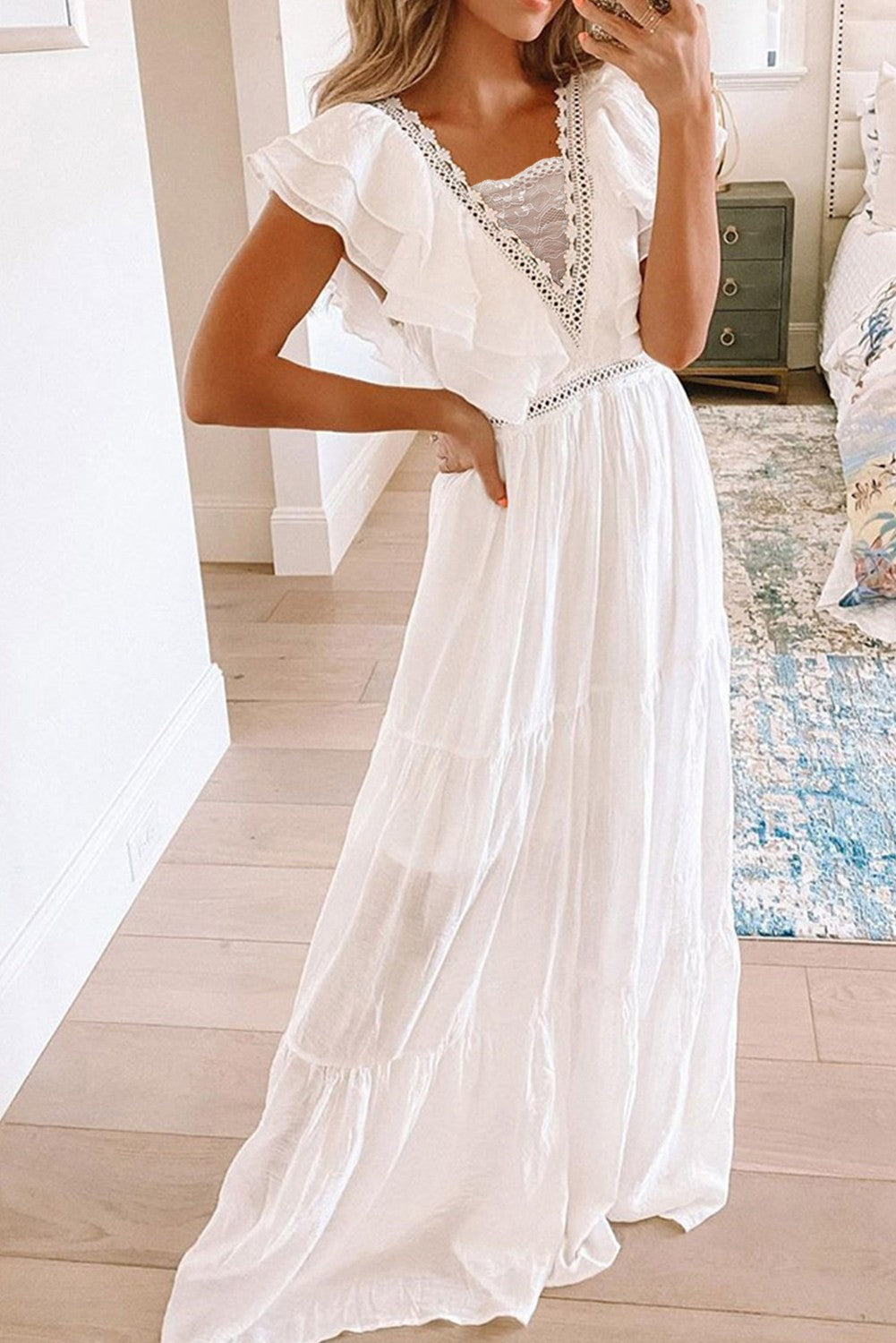 Elegant white maxi dress with ruffles, featuring a fitted top, deep neckline with lace, and a loose baggy skirt.