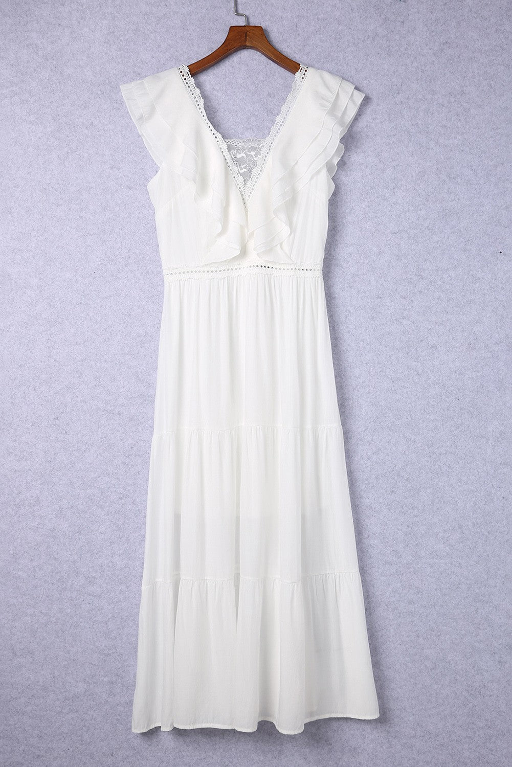 A beautiful white maxi dress featuring decorative ruffles, a deep lace neckline, and a loose baggy skirt, perfect for elegant occasions.