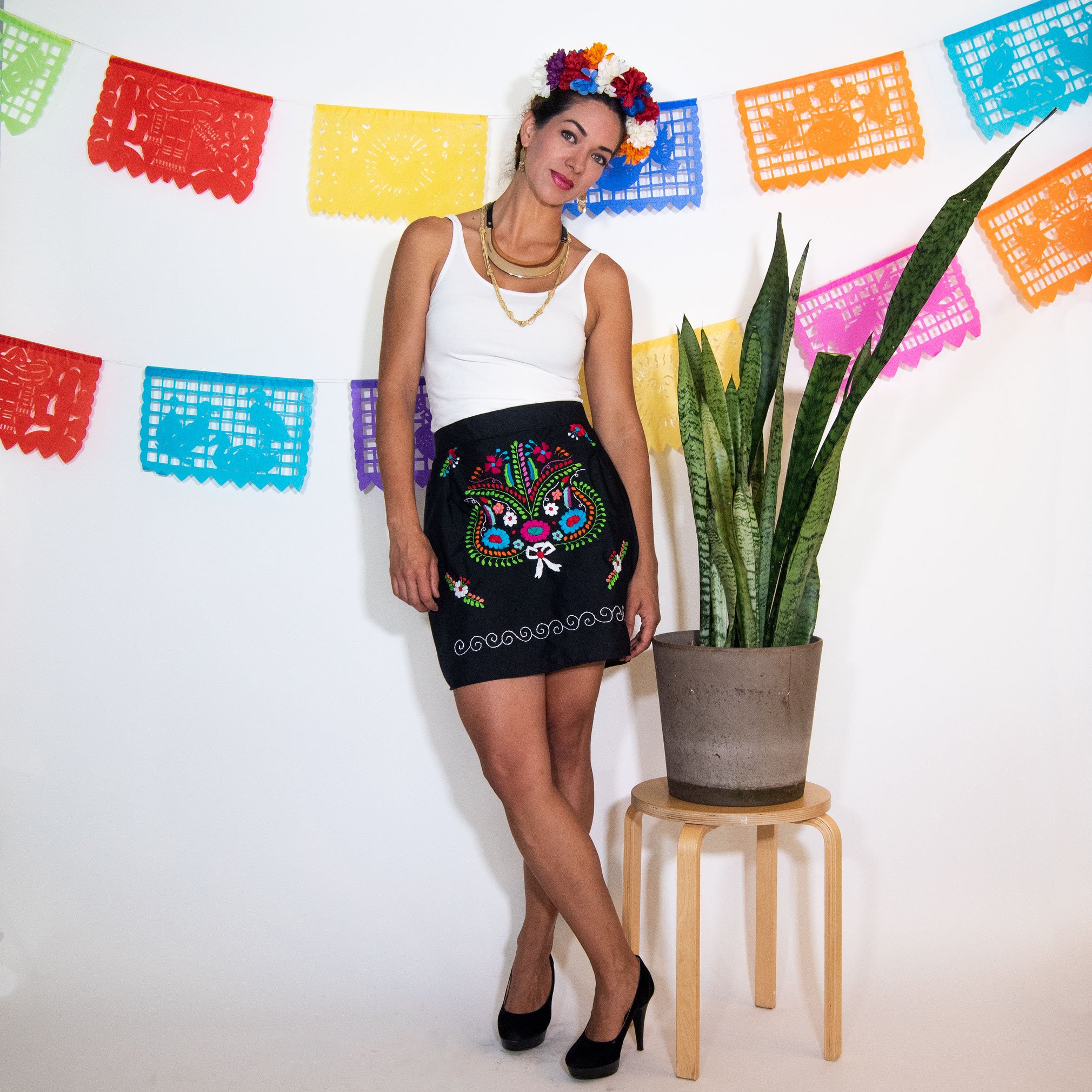 A vibrant Mexican embroidered mini skirt featuring multicolor floral designs on a black background, showcasing unique artisan craftsmanship.