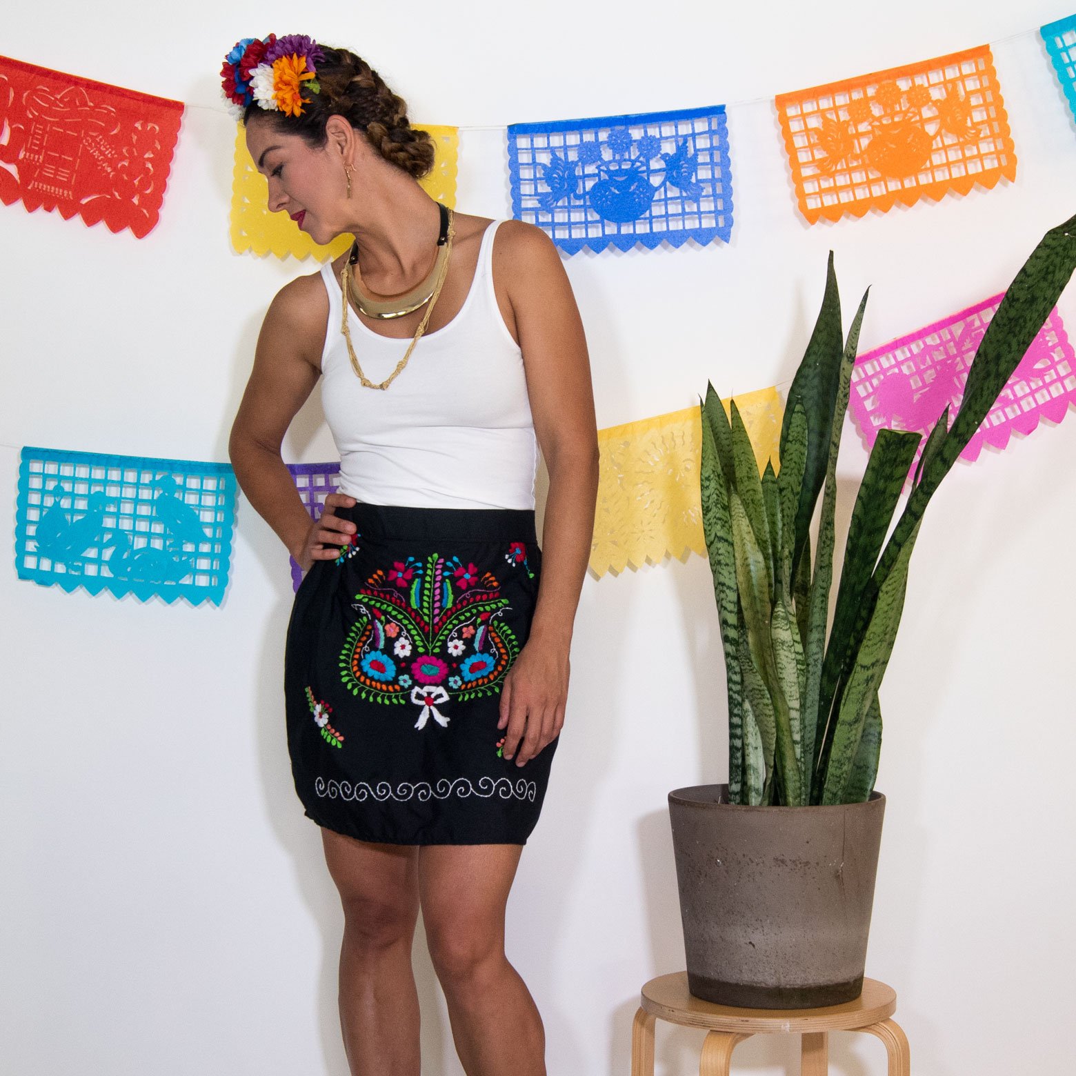 A vibrant Mexican embroidered mini skirt featuring multicolor floral designs on a black background, showcasing unique artisan craftsmanship.