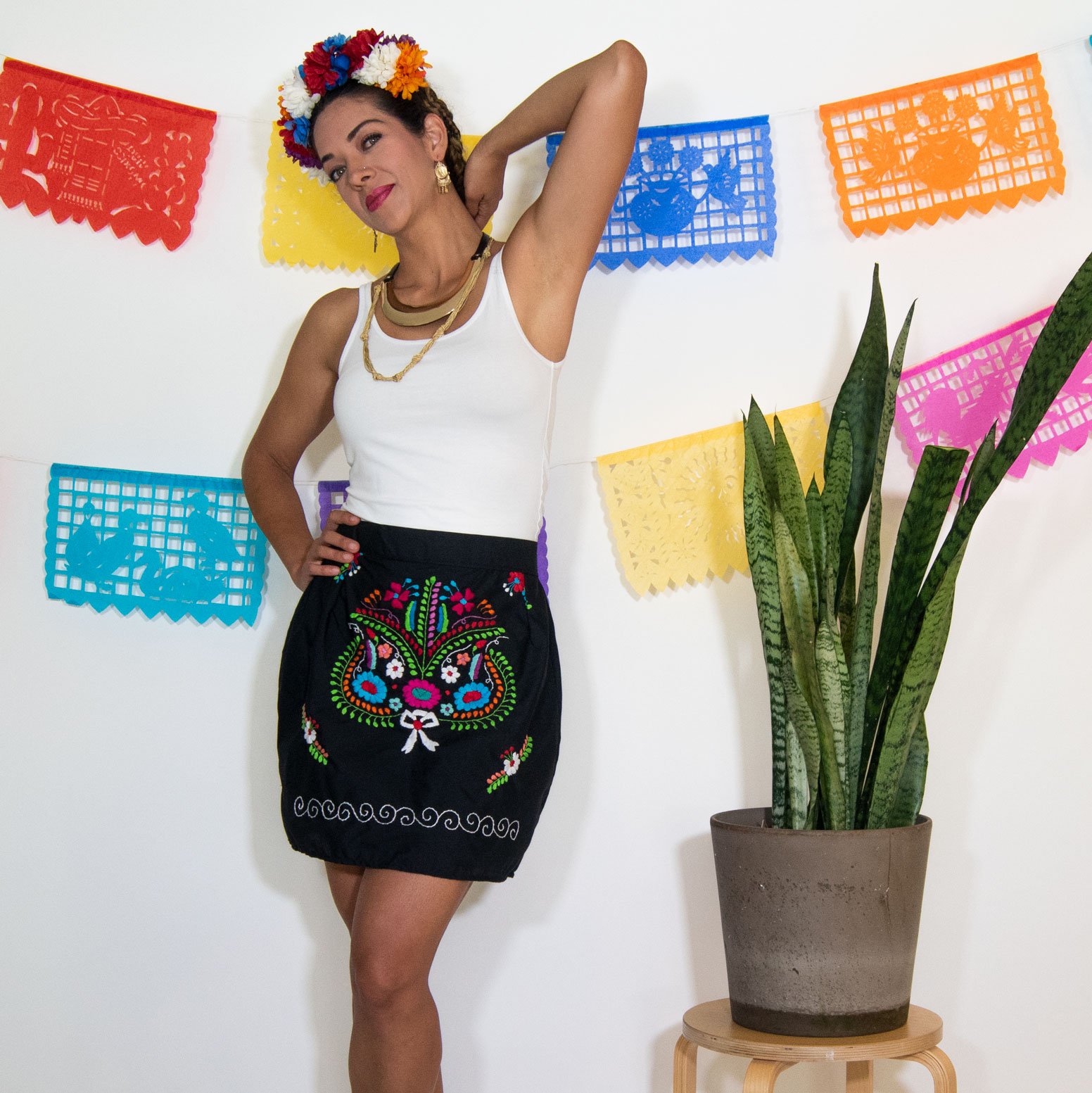 A vibrant Mexican embroidered mini skirt featuring multicolor floral designs on a black background, showcasing unique artisan craftsmanship.