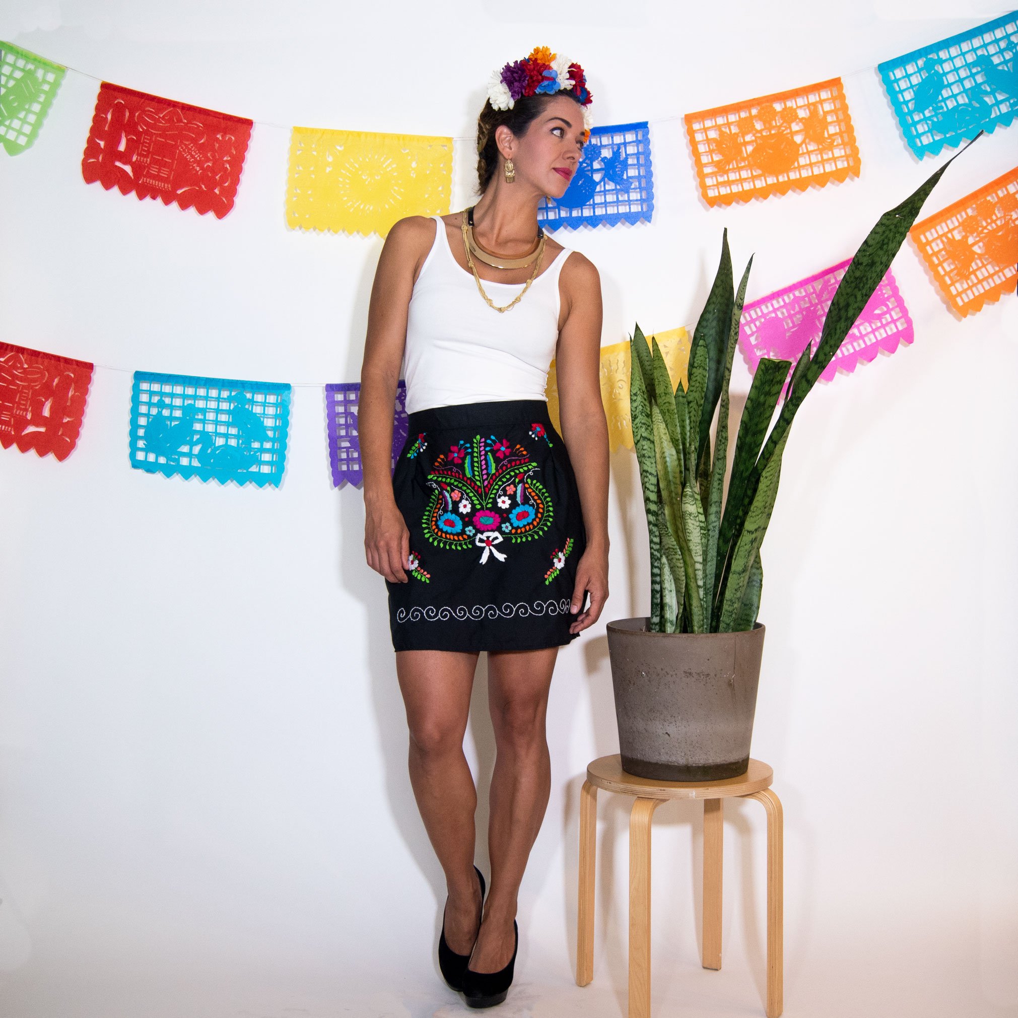 A vibrant Mexican embroidered mini skirt featuring multicolor floral designs on a black background, showcasing unique artisan craftsmanship.