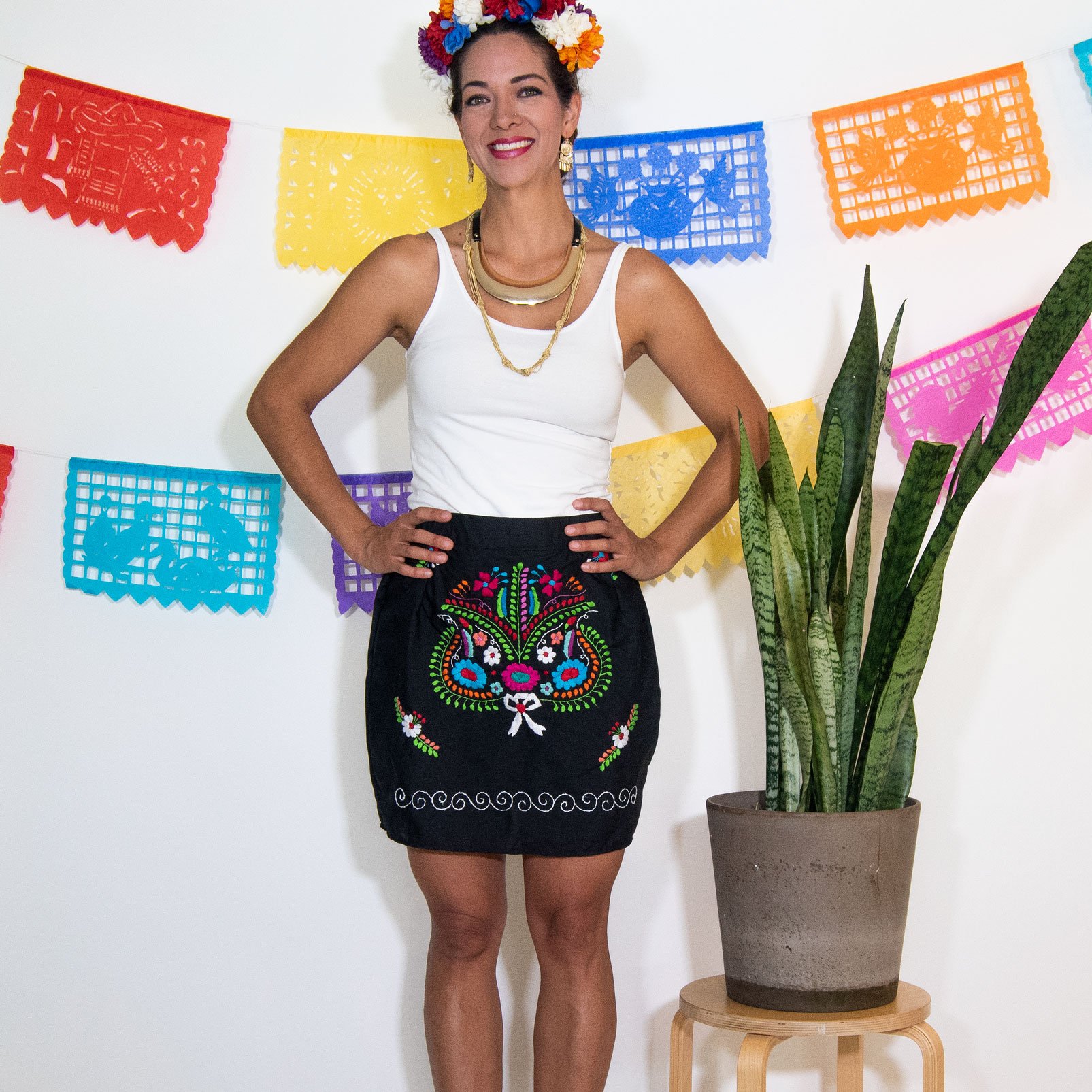 A vibrant Mexican embroidered mini skirt featuring multicolor floral designs on a black background, showcasing unique artisan craftsmanship.