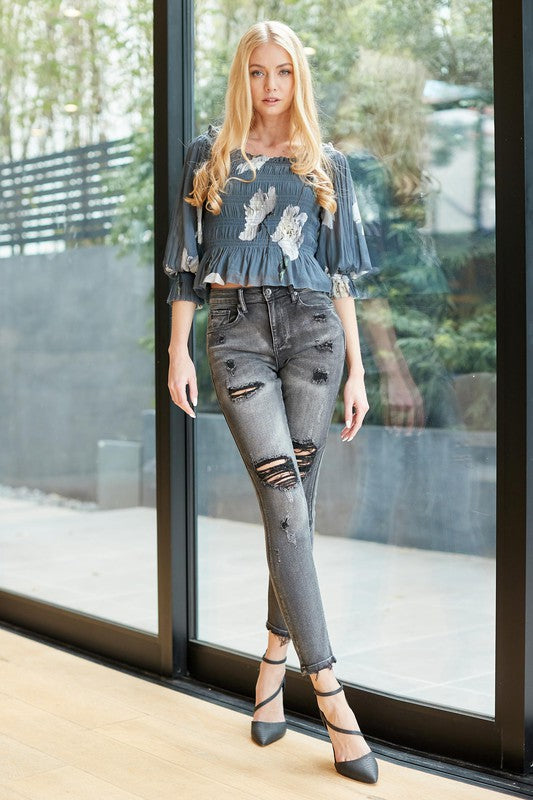 A pair of trendy mid-rise skinny grey denim jeans with distressed details, showcasing a stylish and modern design.