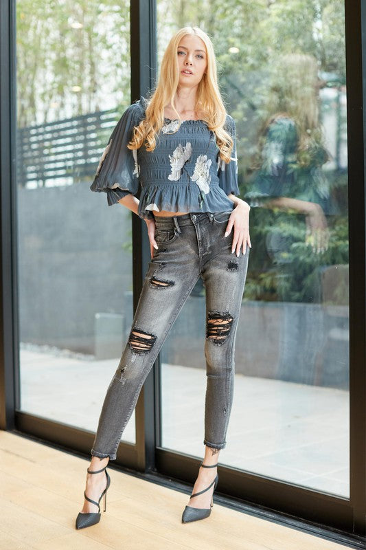 A pair of trendy mid-rise skinny grey denim jeans with distressed details, showcasing a stylish and modern design.