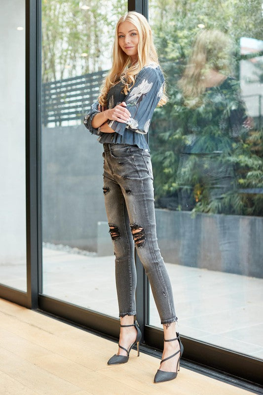 A pair of trendy mid-rise skinny grey denim jeans with distressed details, showcasing a stylish and modern design.