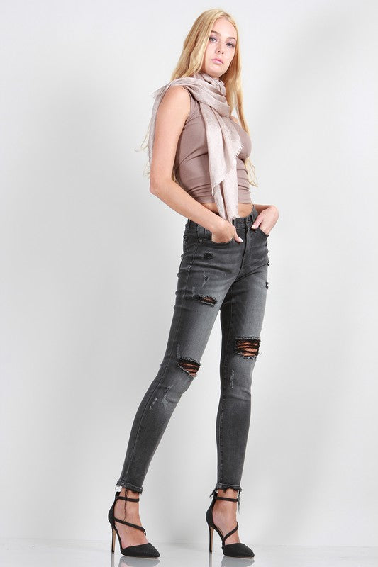 A pair of trendy mid-rise skinny grey denim jeans with distressed details, showcasing a stylish and modern design.