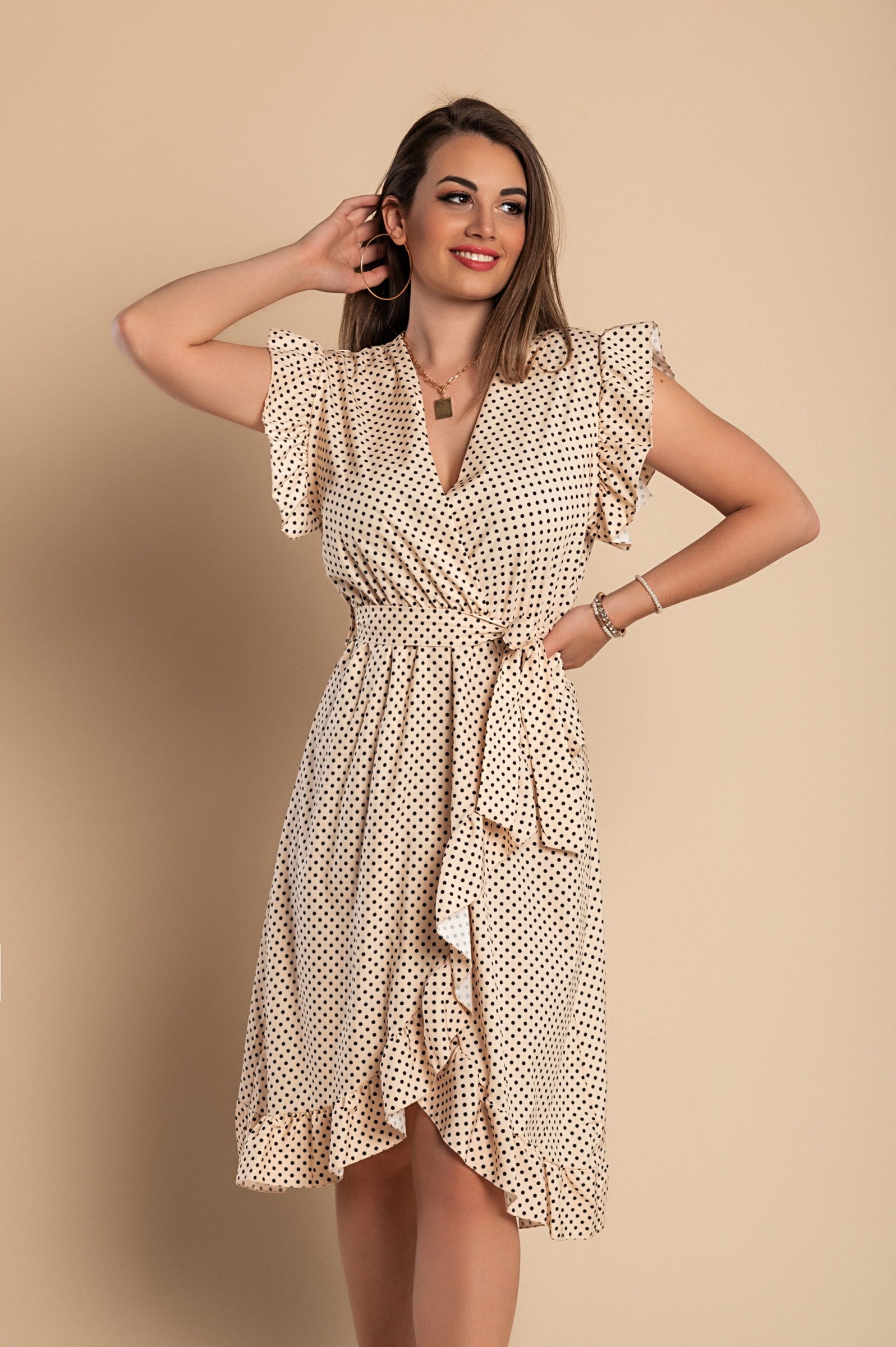 Beige midi dress with polka dot print featuring a deep V-neckline, ruffled sleeves, and a flowing skirt, elegantly displayed on a mannequin.