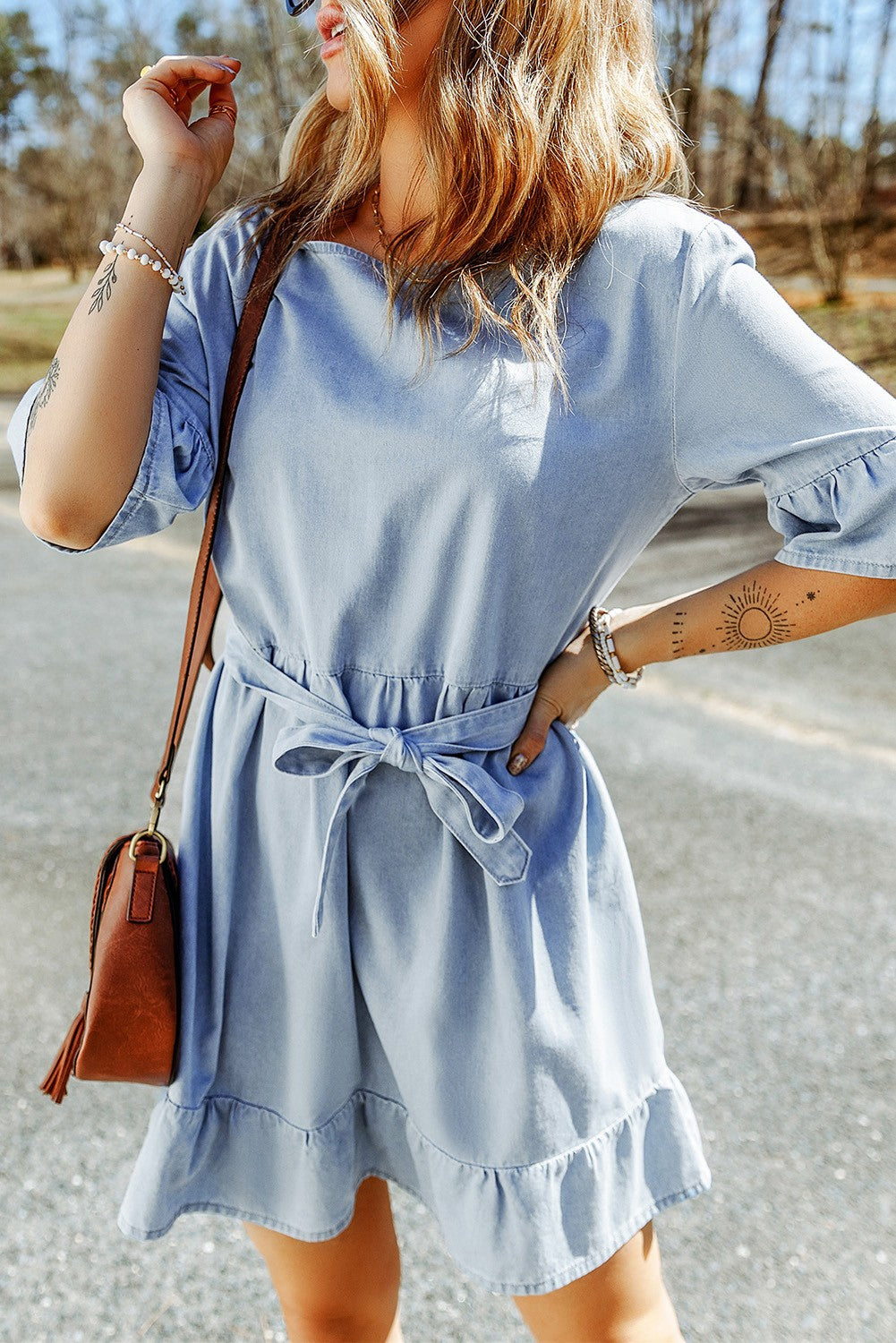 Light blue mini denim dress with ruffles, featuring a scoop neckline, 3/4 sleeves, and a decorative belt.