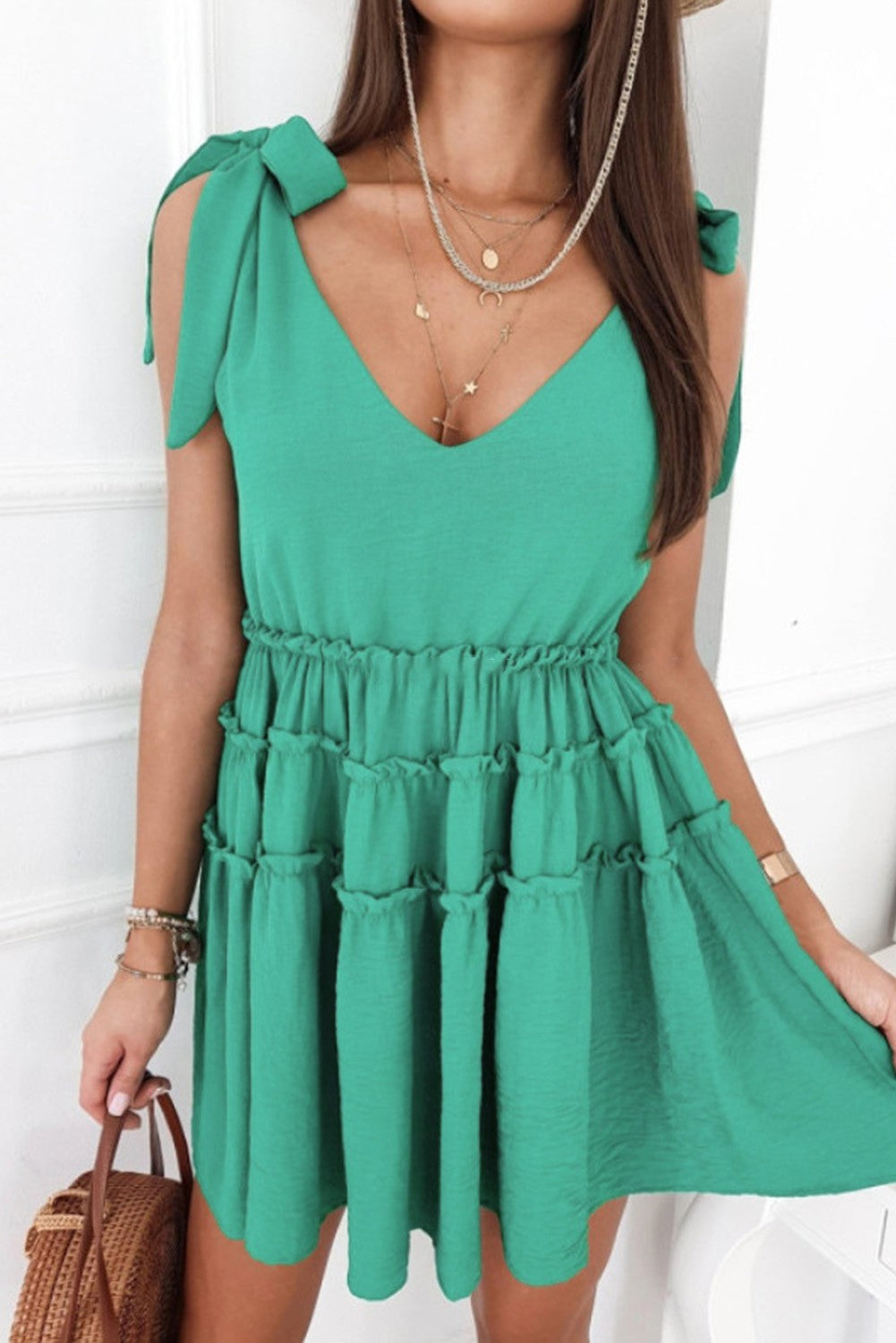 A stylish green mini dress featuring ruffles, a round neckline, and bow-tied straps, perfect for casual and formal occasions.